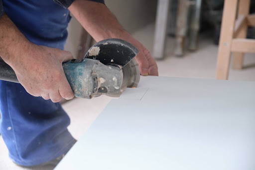 A person cutting a tile with an angle grinder