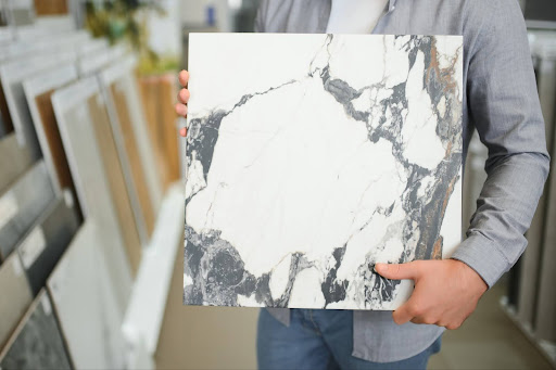 A person holding a large format tile to show size options