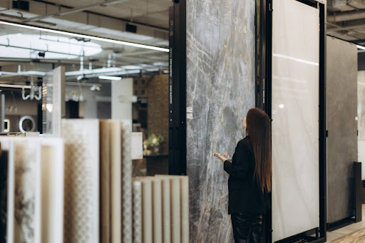 A woman viewing a large format grey marble-effect tile slab at a tile shop showroom in Singapore