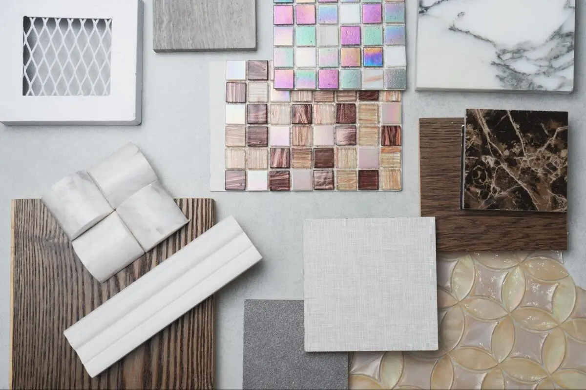 A flat lay of decorative mosaic tiles and marble slabs for cost and design evaluation in a tile shop.
