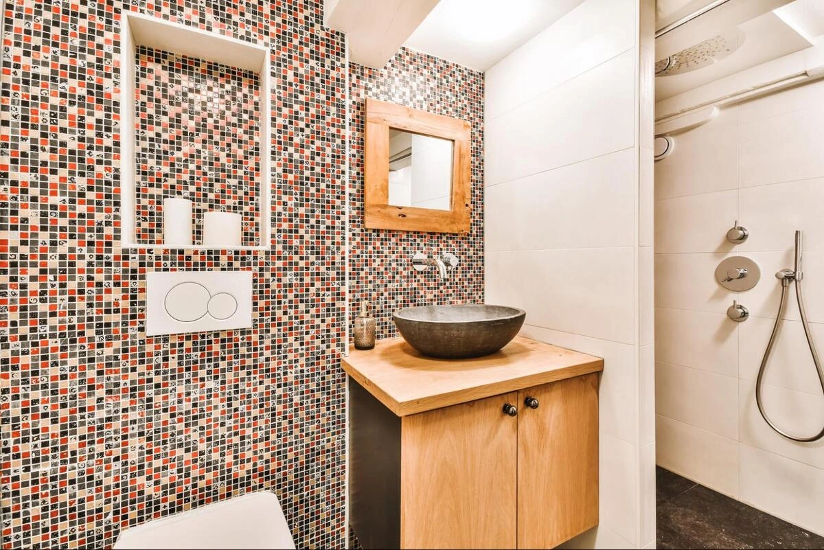 Bathroom with red, black and white mosaic tile feature wall and wood vanity