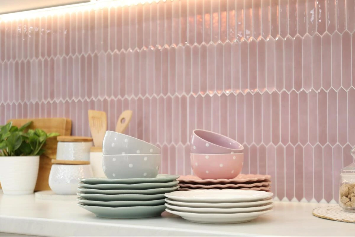 Pink picket-shaped mosaic tile kitchen splashback with ceramic bowls and plates