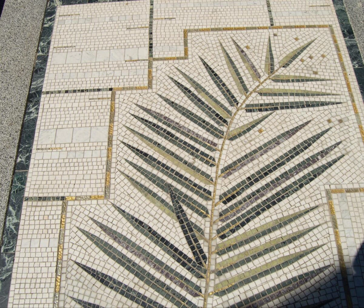 Marble and gold mosaic tile floor with a palm leaf pattern